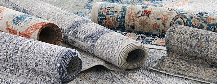 Rolled rugs with intricate patterns displayed on a flat surface.