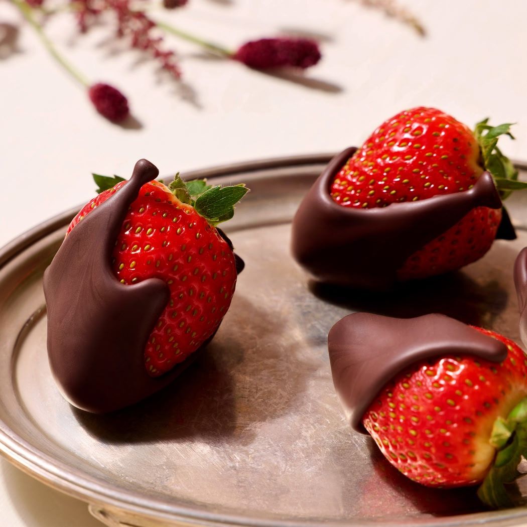 Hexagonal box with chocolate-covered strawberries and a ribbon.