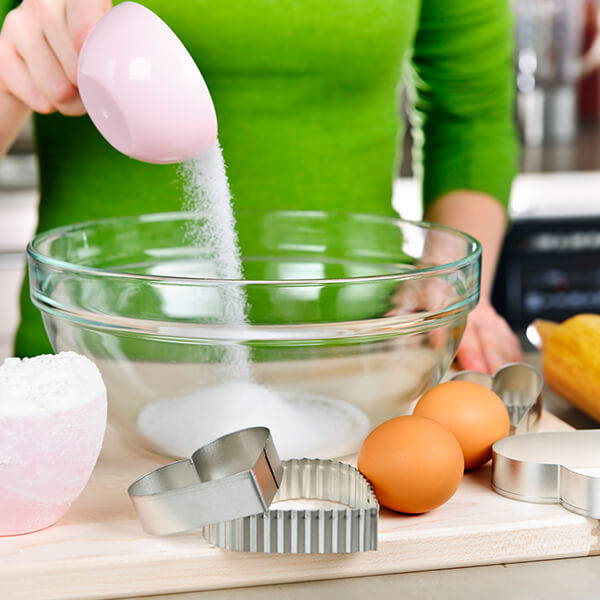 High Quality Organics Express woman pouring sugar into a bowl to bake