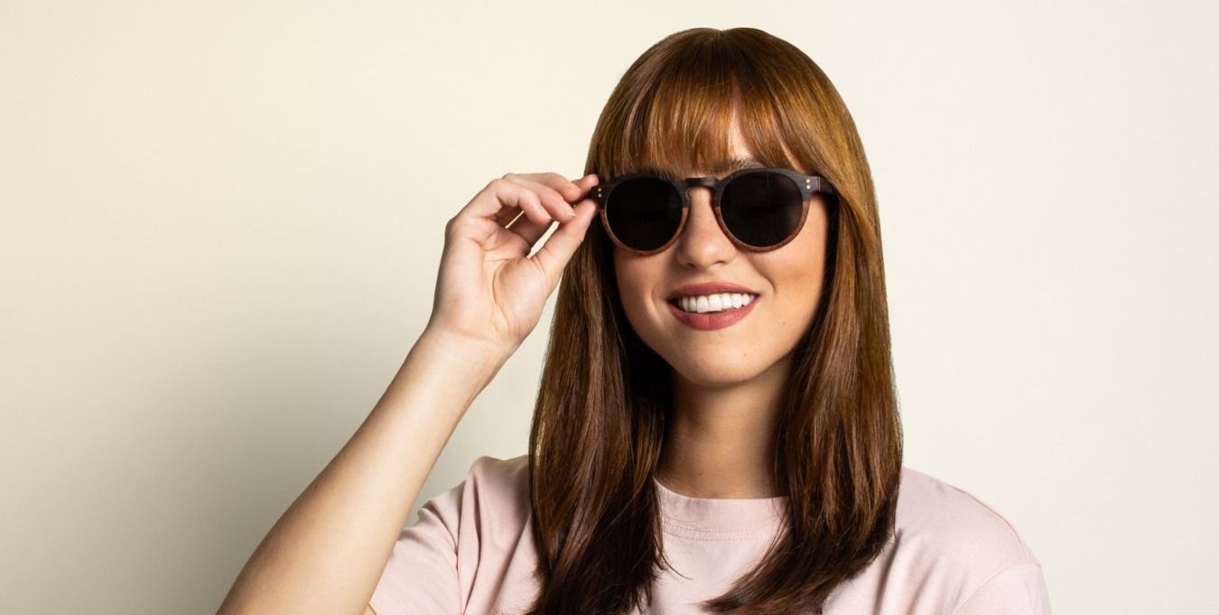 woman wearing round sunglasses and smiling