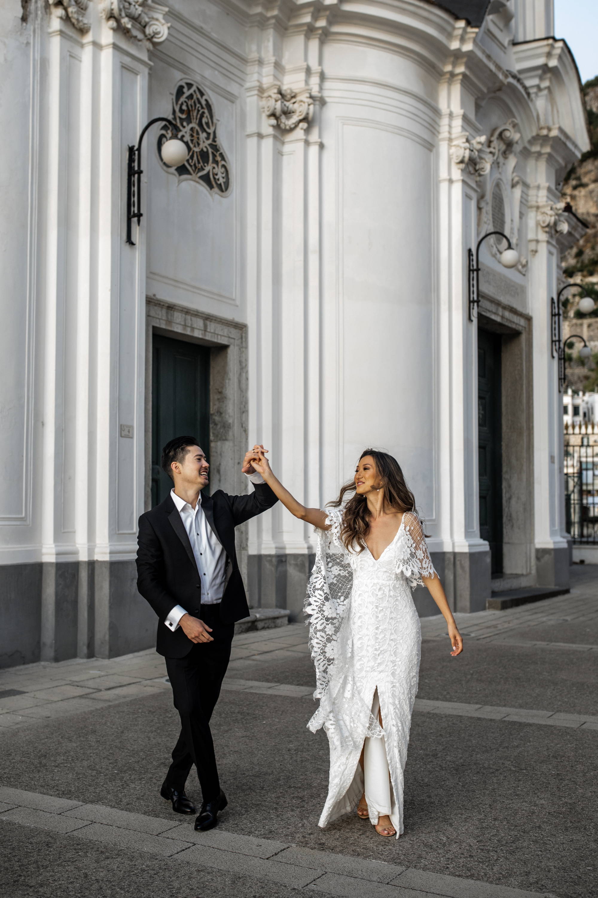 Novio con traje negro y camisa blanca dando vueltas a su novia