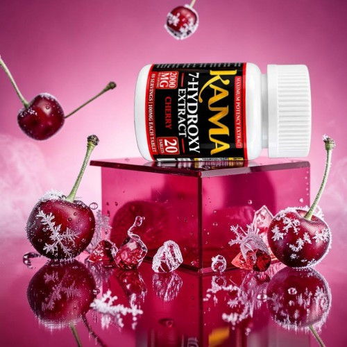 Bottle of Kama Hydroxy with cherries and decorative ice on a pink background.