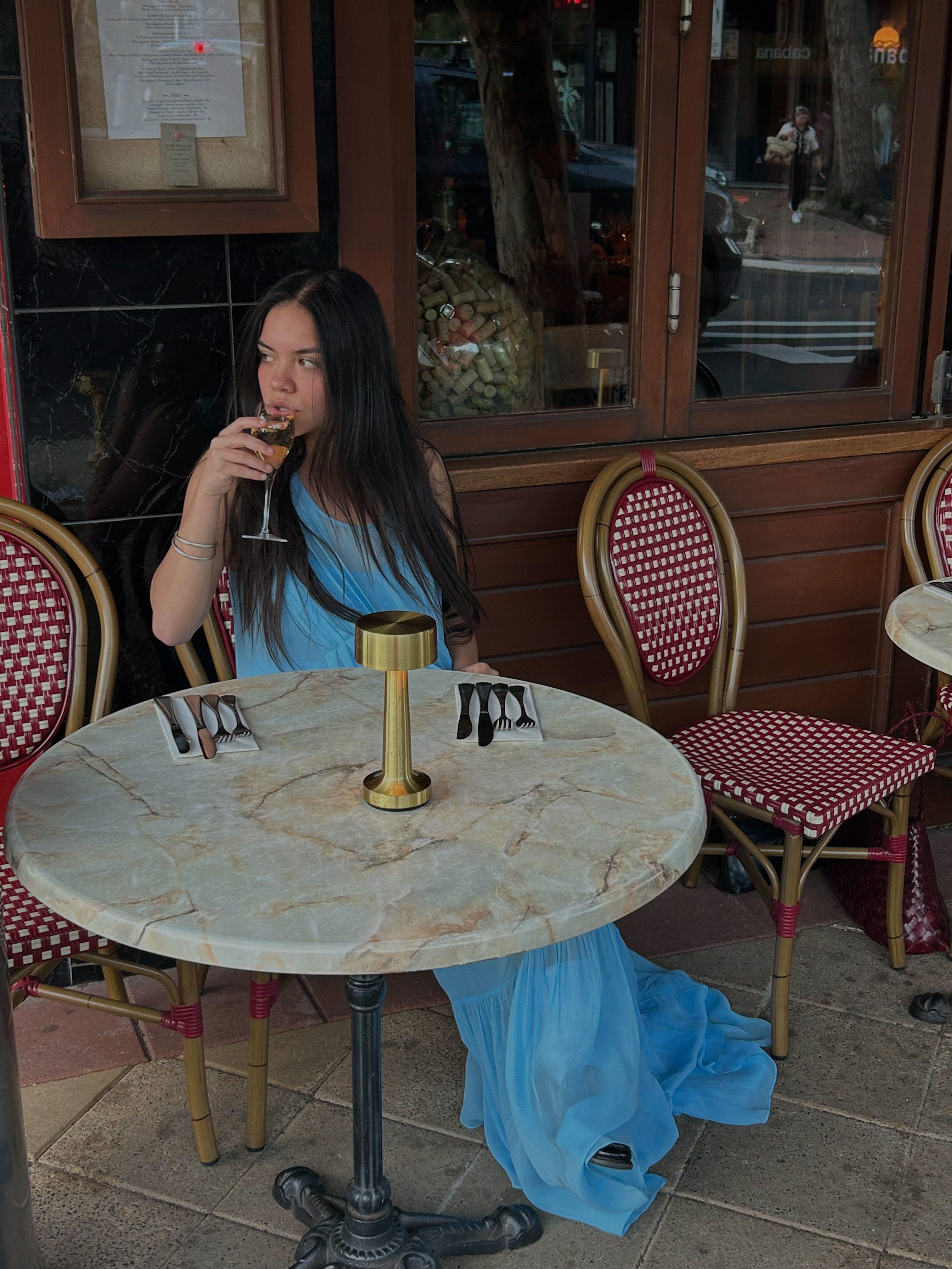Frankie sits outside restaurant Bistro Boulevard wearing the Jena Cami Dress in Sky.
