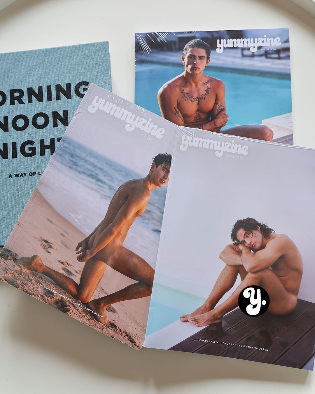 Three magazines featuring male models by the beach.