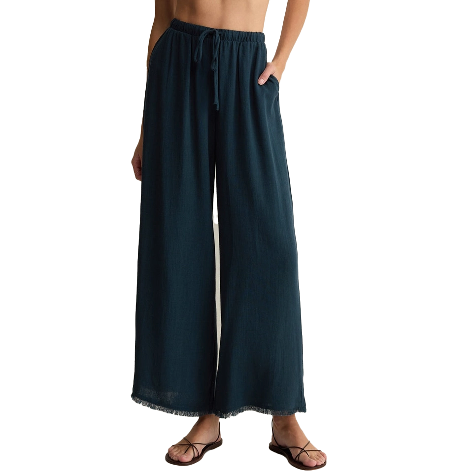 Woman wearing dark teal wide-leg pants with pockets and sandals.
