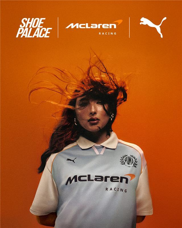 Person in McLaren Racing jersey with flowing hair against an orange background.