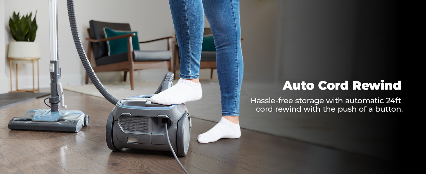 Person using a vacuum with auto cord rewind feature.