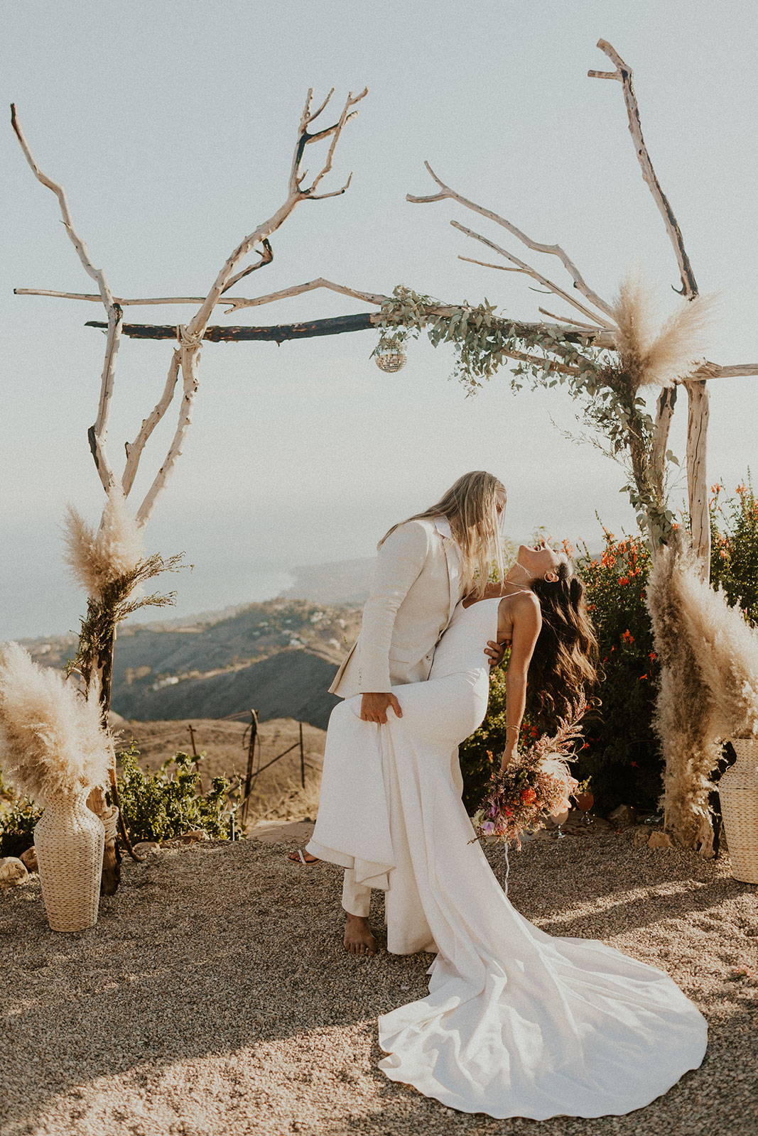 Bride and groom in front of wooden stick arbor