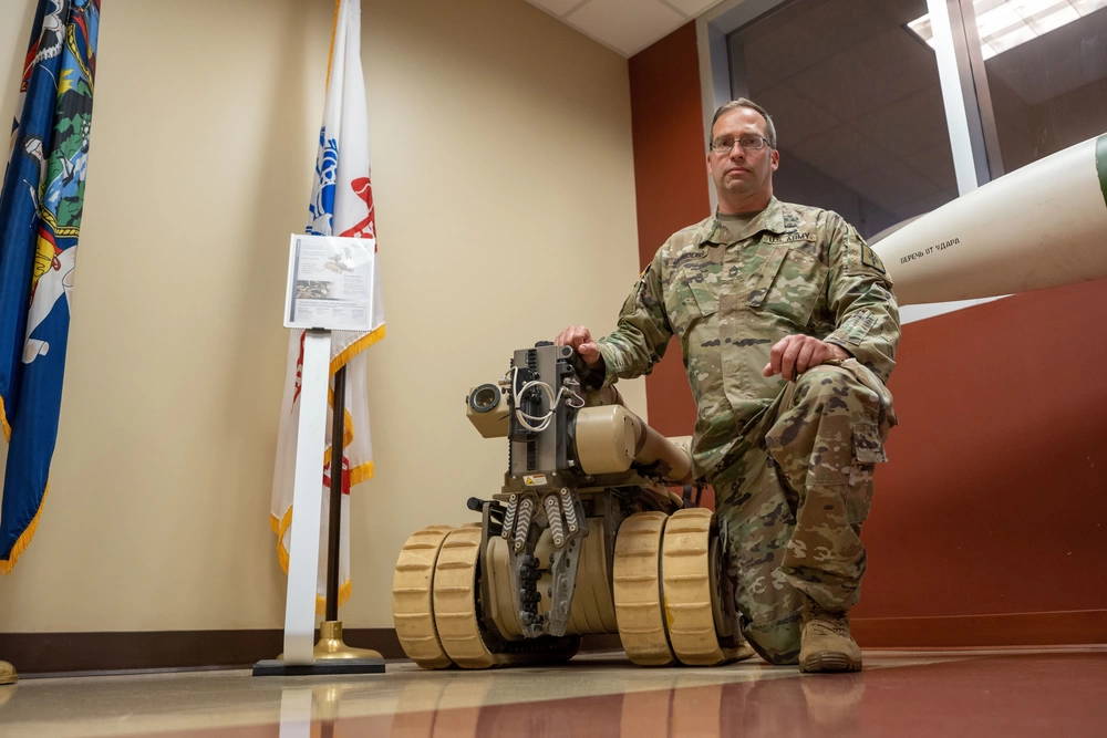 U.S. Army Master Sgt. Eric Lautenschlager, the senior noncommissioned officer assigned to the 501st Ordnance Battalion, takes a knee next to the iRobot 710 Warrior, an explosive ordnance disposal remotely controlled machine at the Armed Forces Reserve Center in Glenville N.Y. on June 10, 2021. Members of the 501st Ordnance Battalion are trained to provide mission command, and supervision of Explosive Ordnance Disposal (EOD) operations and functions to include administration and logistical support of assigned units. (U.S. Army National Guard photo by Sgt. Sebastian Rothwyn)