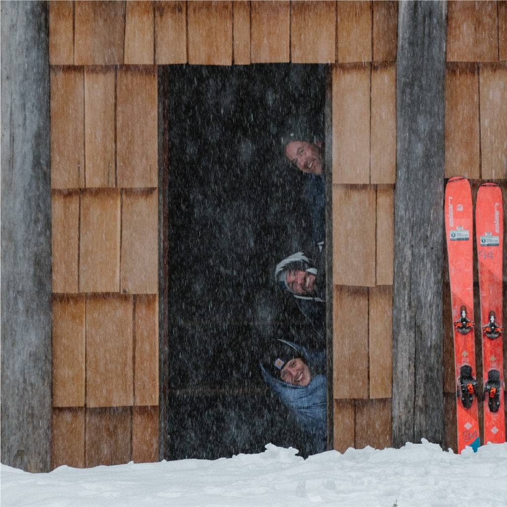 Three people inside ski cabin wrapped in blankets