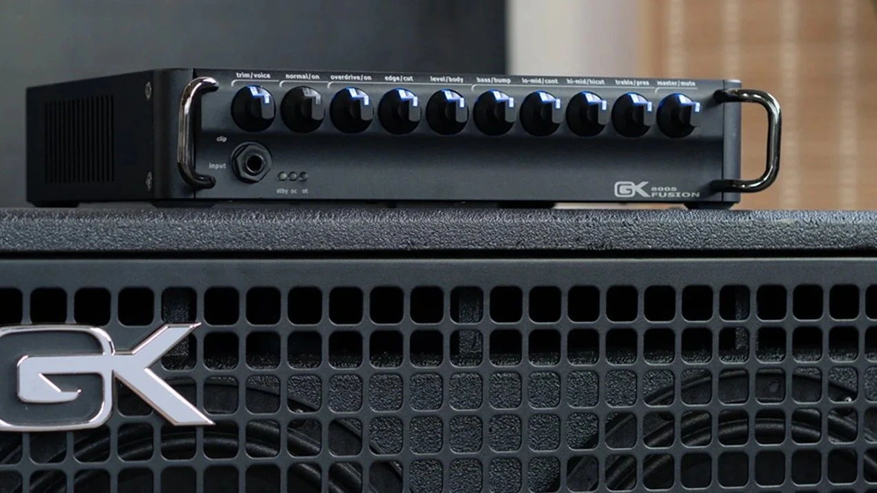 Black amplifier with knobs on top of a speaker cabinet.