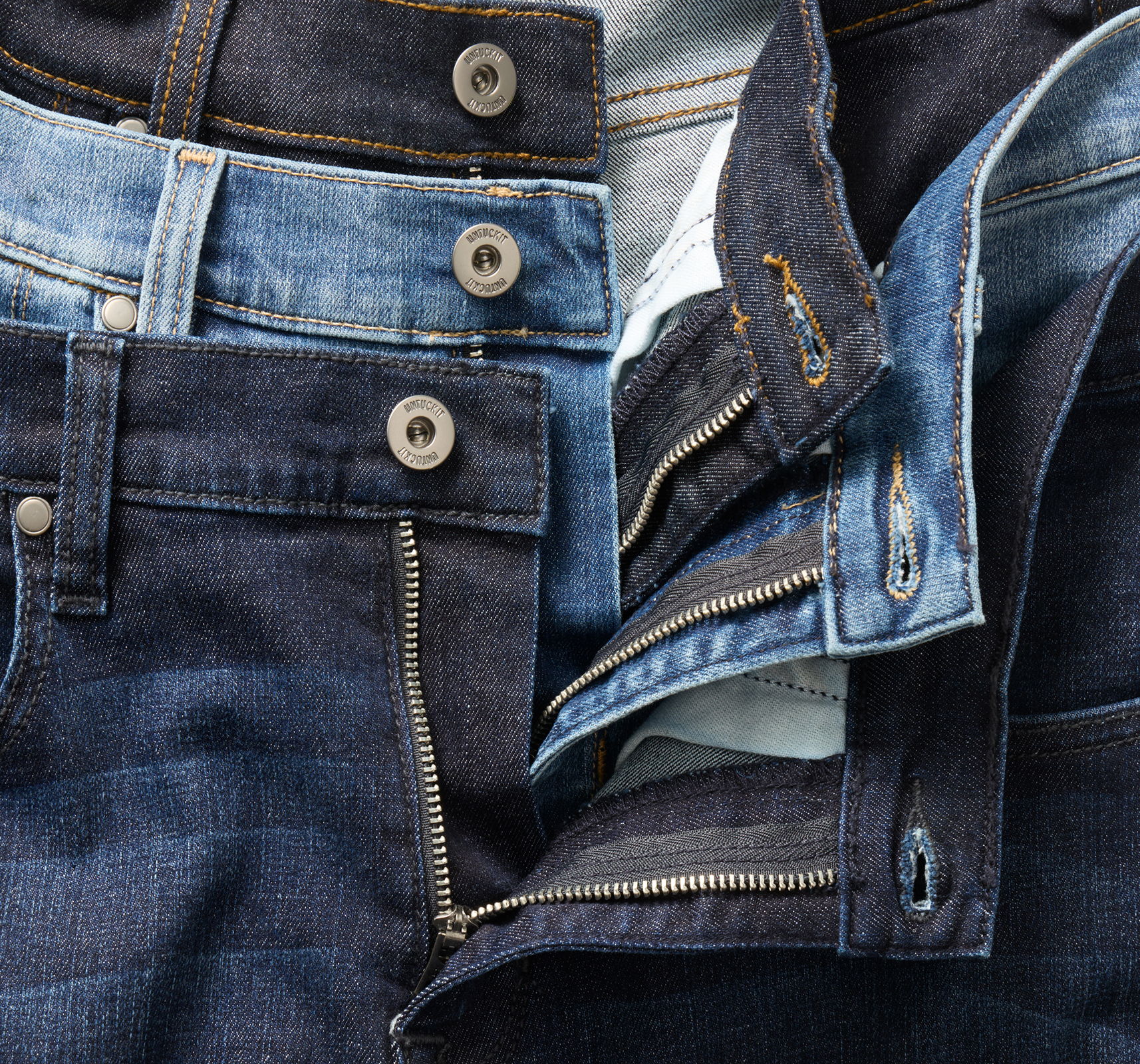 A collection of various denim jeans with visible buttons and zippers.