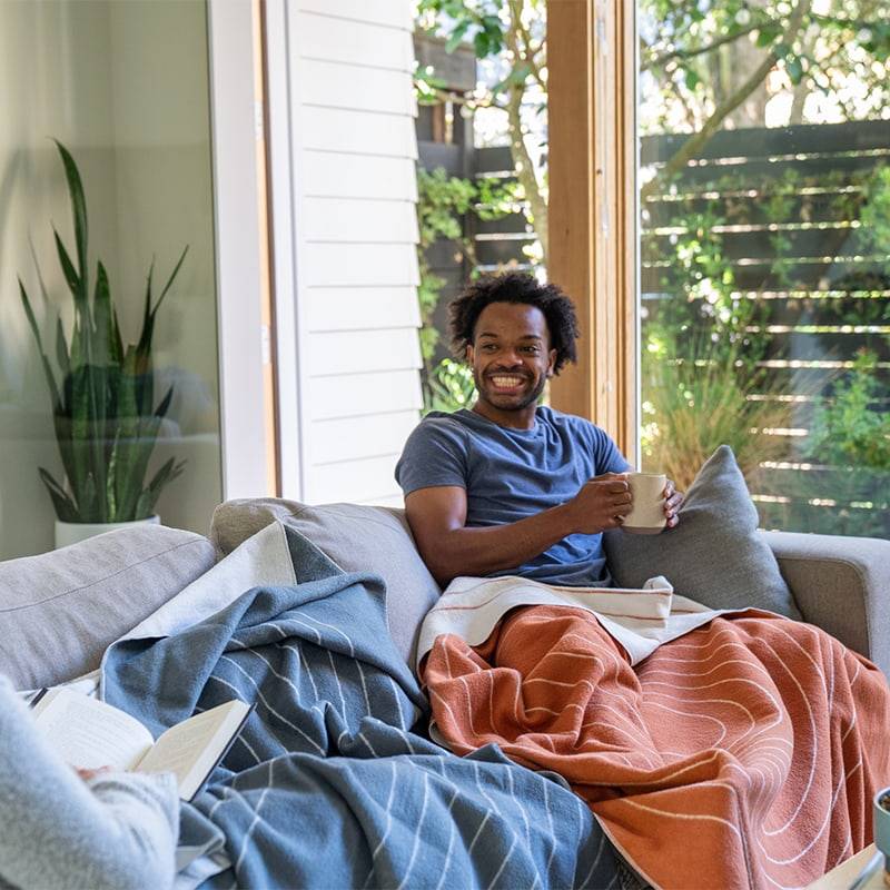 Man smiling under SoftWool Blanket on couch