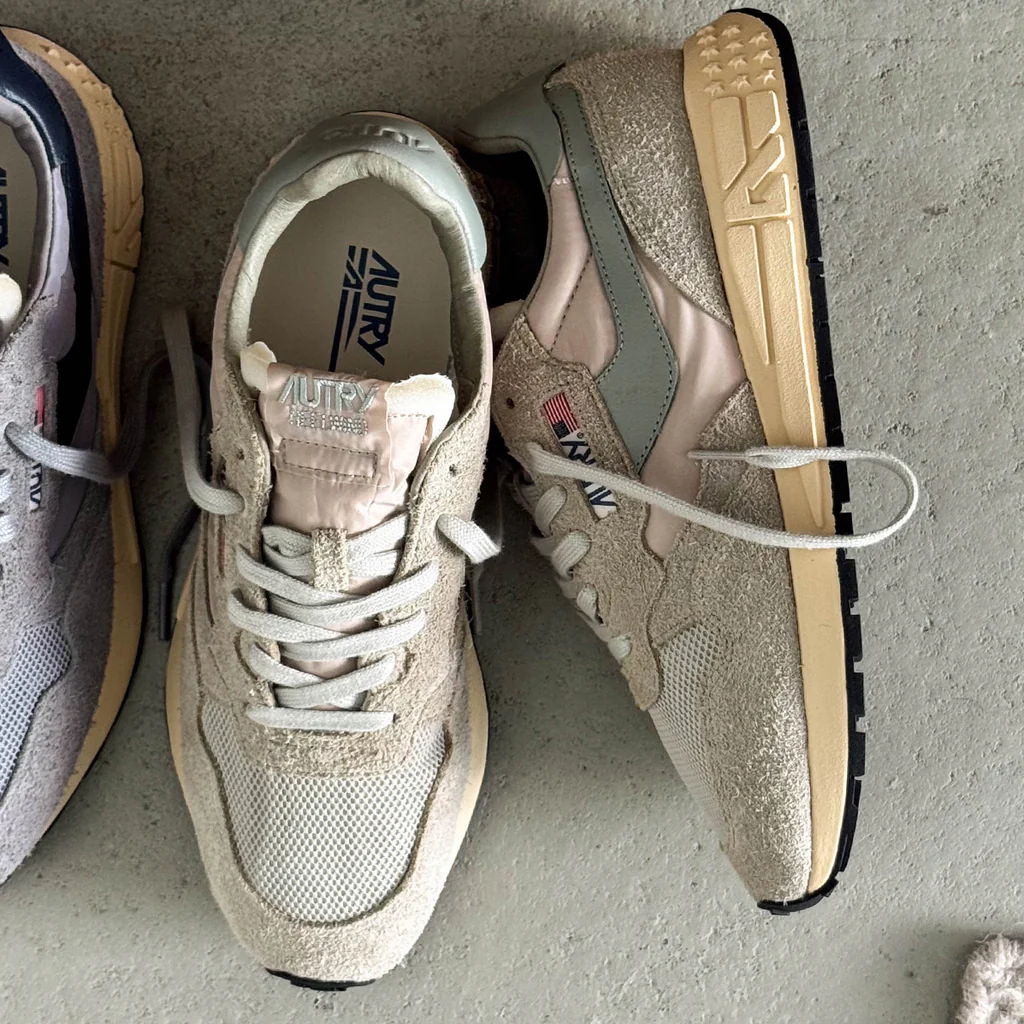 A pair of sneakers in neutral colors on a concrete surface.