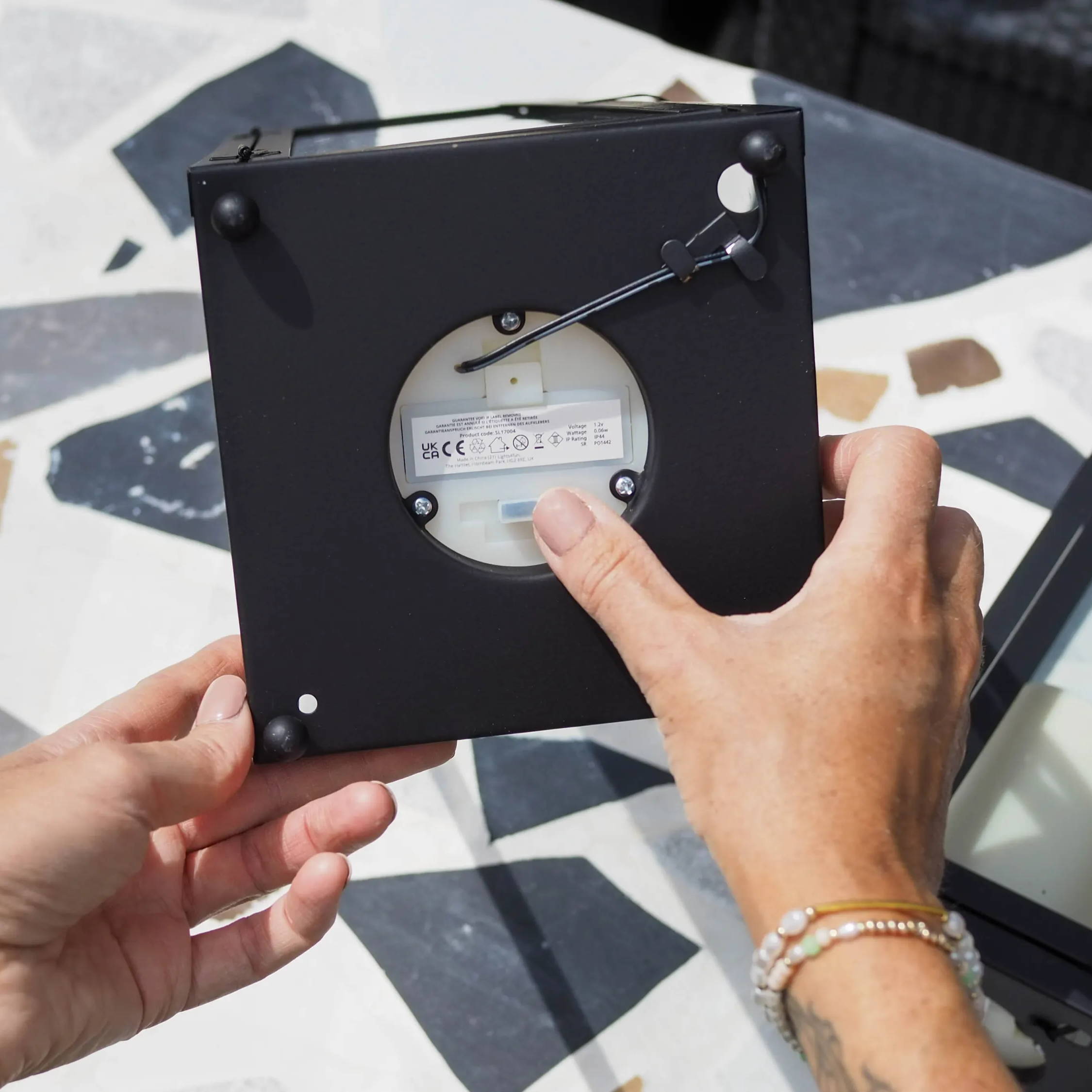 Person turning the solar switch to ON at the base of a lantern.