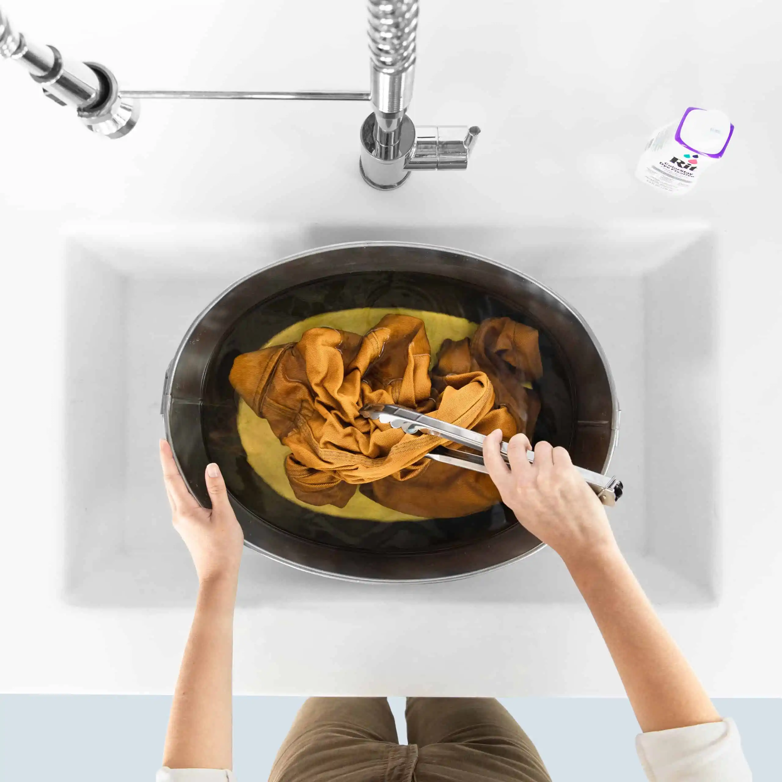 Person using tongs to handle fabric in a sink.