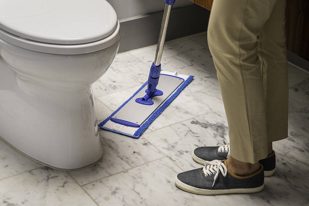 person cleaning toilet floor with microfiber mop