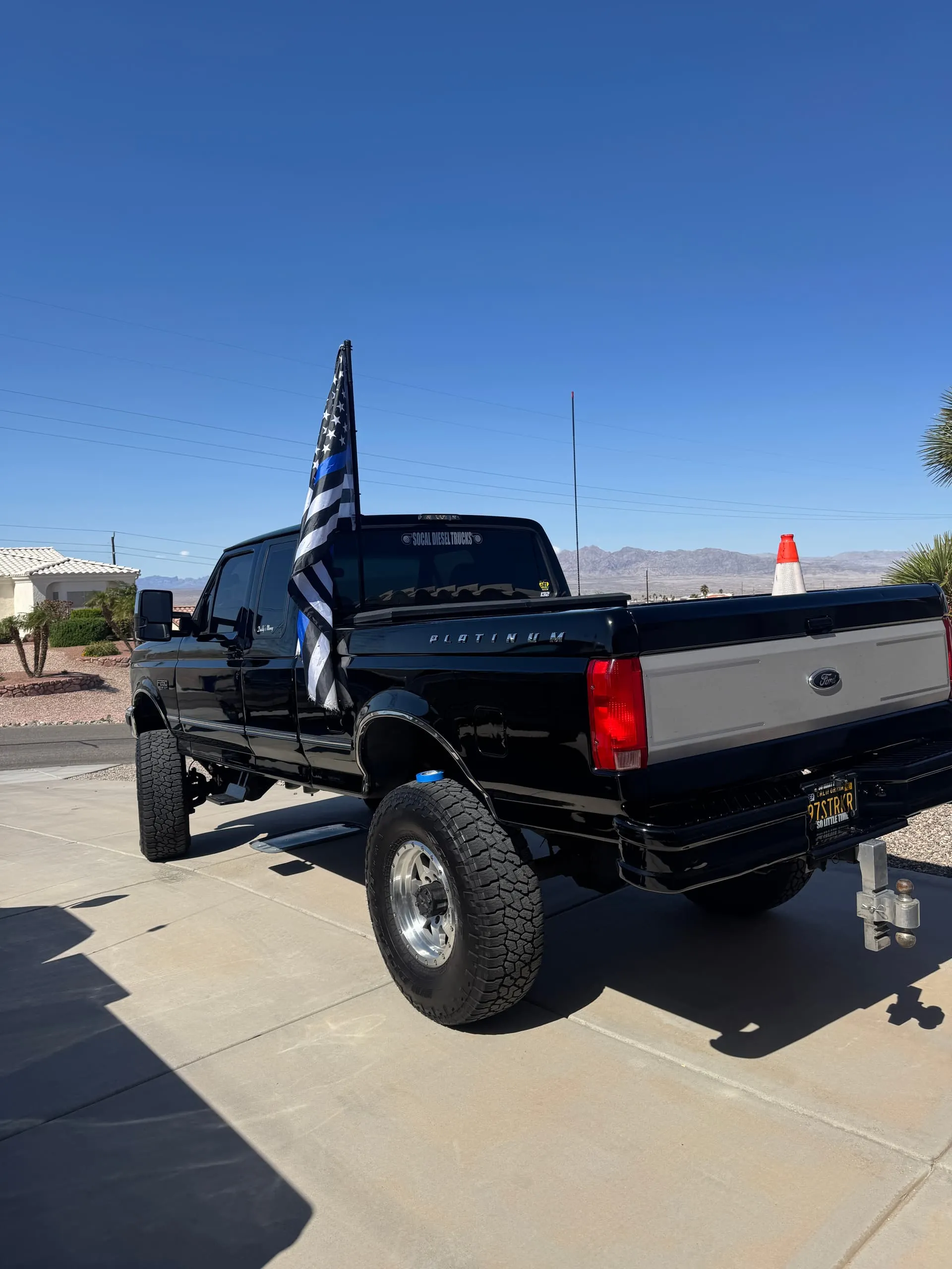 Rear view of Noah's lifted black 1997 Ford F250 with Thin Blue Line flag and SOCAL DIESEL TRUCKS decal