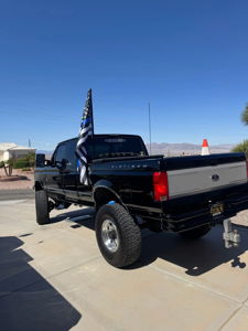 Rear view of Noah's lifted black 1997 Ford F250 with Thin Blue Line flag and SOCAL DIESEL TRUCKS decal