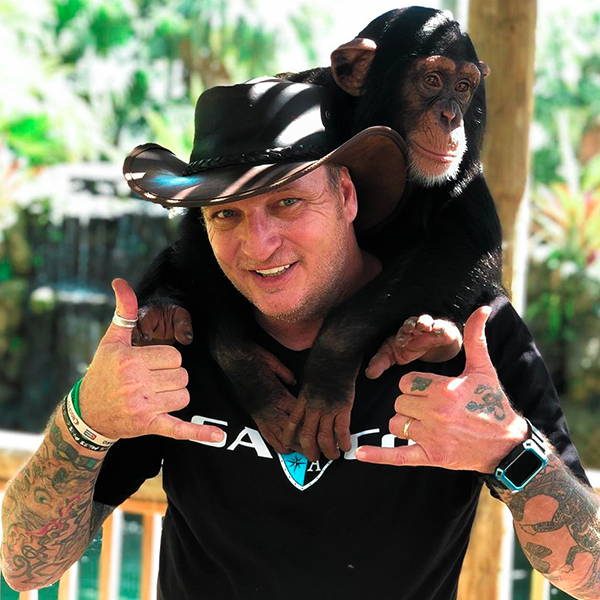 Robbie Keszey carrying a monkey over his shoulders while wearing an SA Company short sleeve cotton shirt.