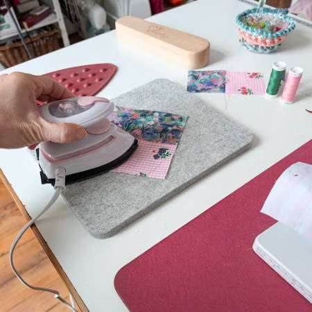 the seams of a quilt block pressed with a mini iron on a wool pressing mat