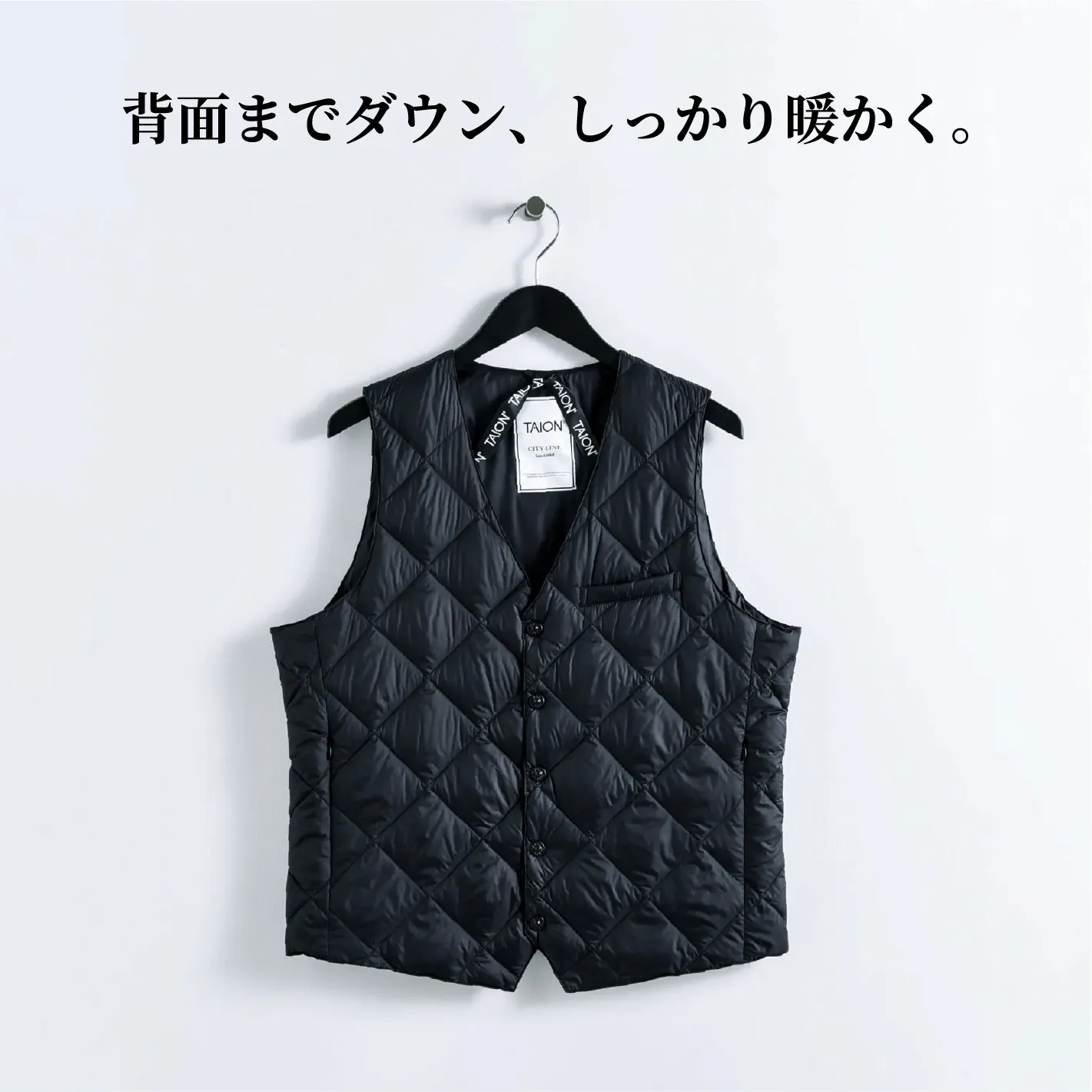 Black quilted vest hanging on a hook against a white background.