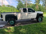 Side profile Caitlyn's lifted white Silverado with teal wheels and fender flares photo 2