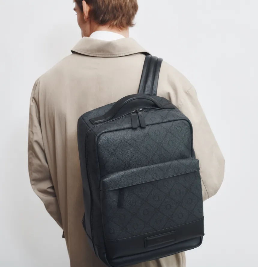 Person wearing a beige coat with a black backpack, viewed from behind.