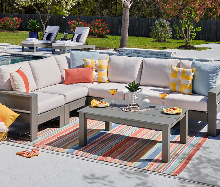 Outdoor seating area with a sectional sofa, coffee table, and decorative pillows.