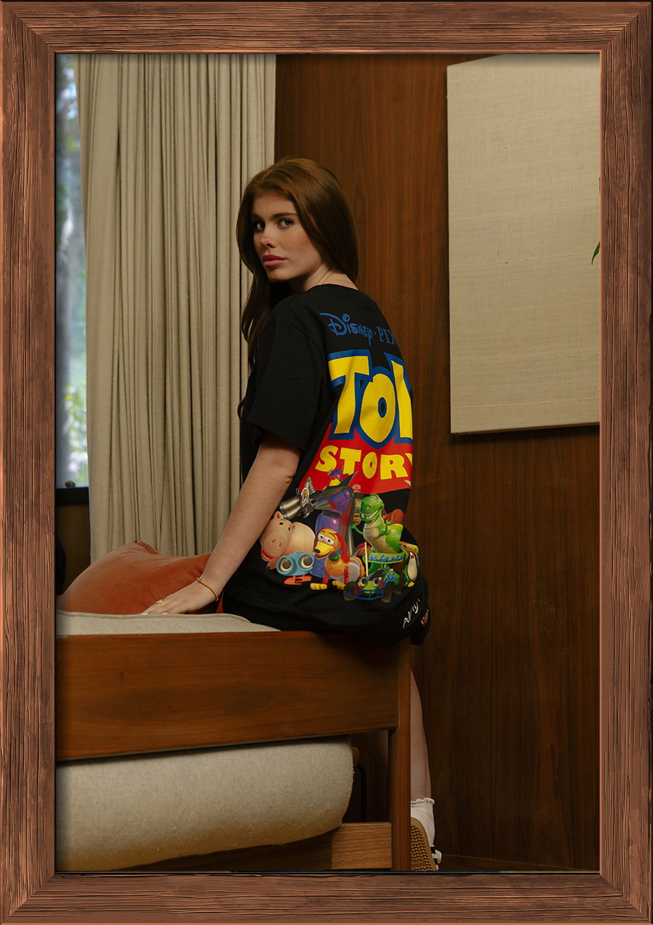 Person sitting on a bed wearing a Toy Story t-shirt.