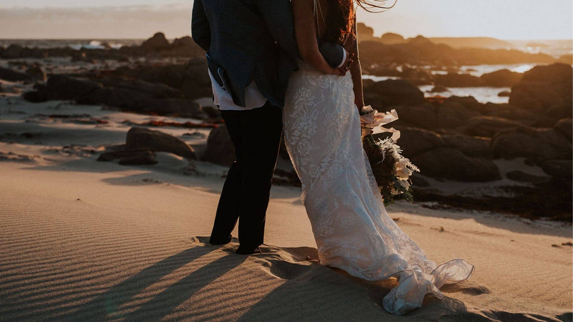 Bride wearing lace dress on the sand