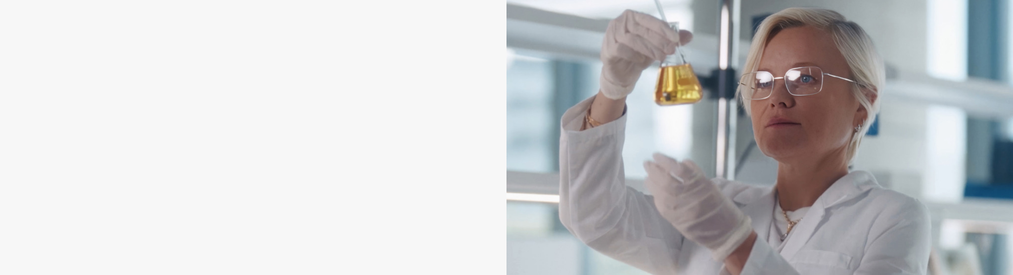 Scientist in a lab coat conducting an experiment with a test tube.