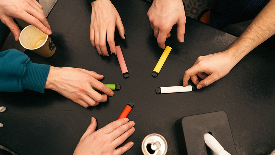 A picture of a group of people reaching for prefilled vape devices.