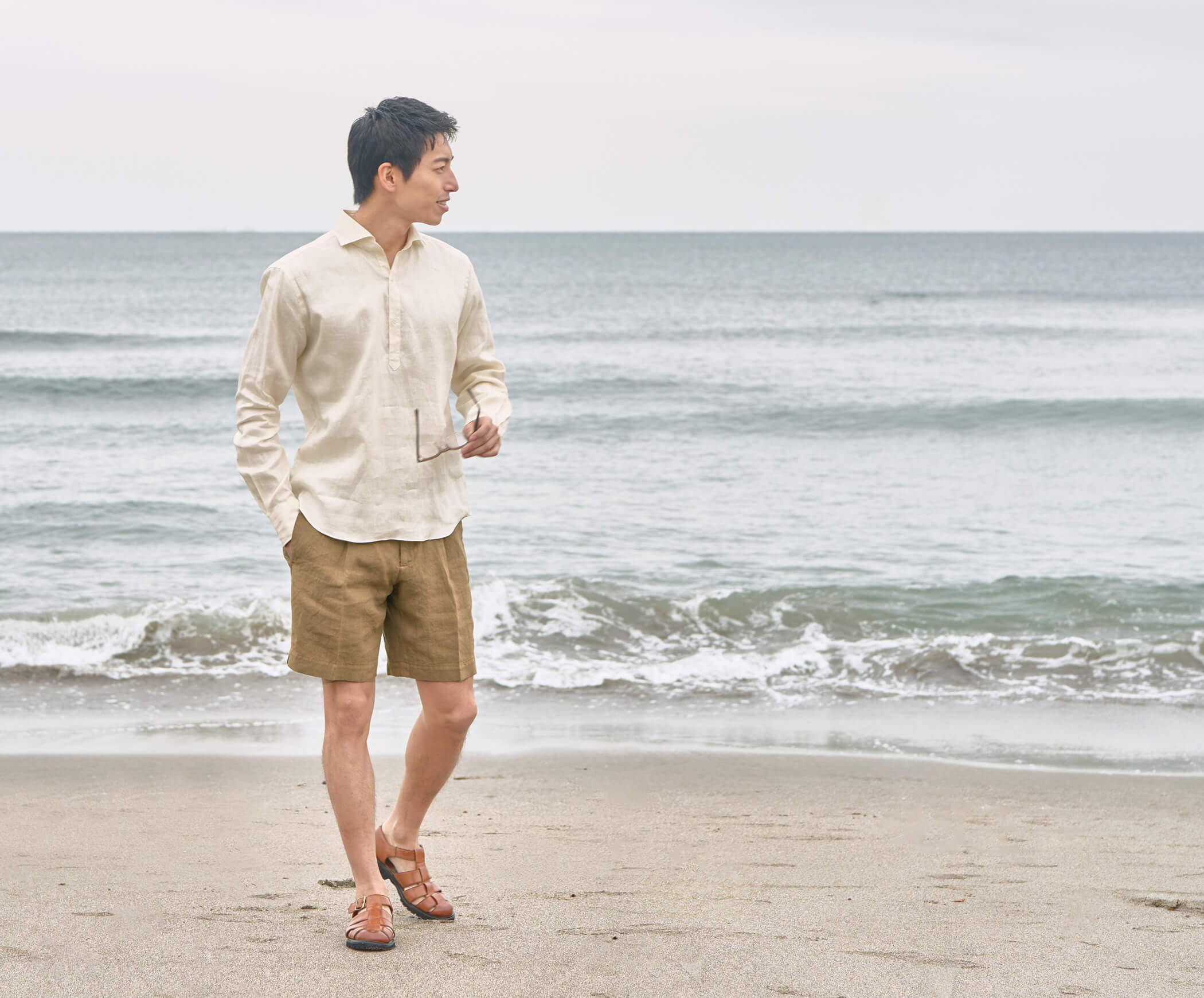 Person walking on the beach near the water, wearing casual clothing.
