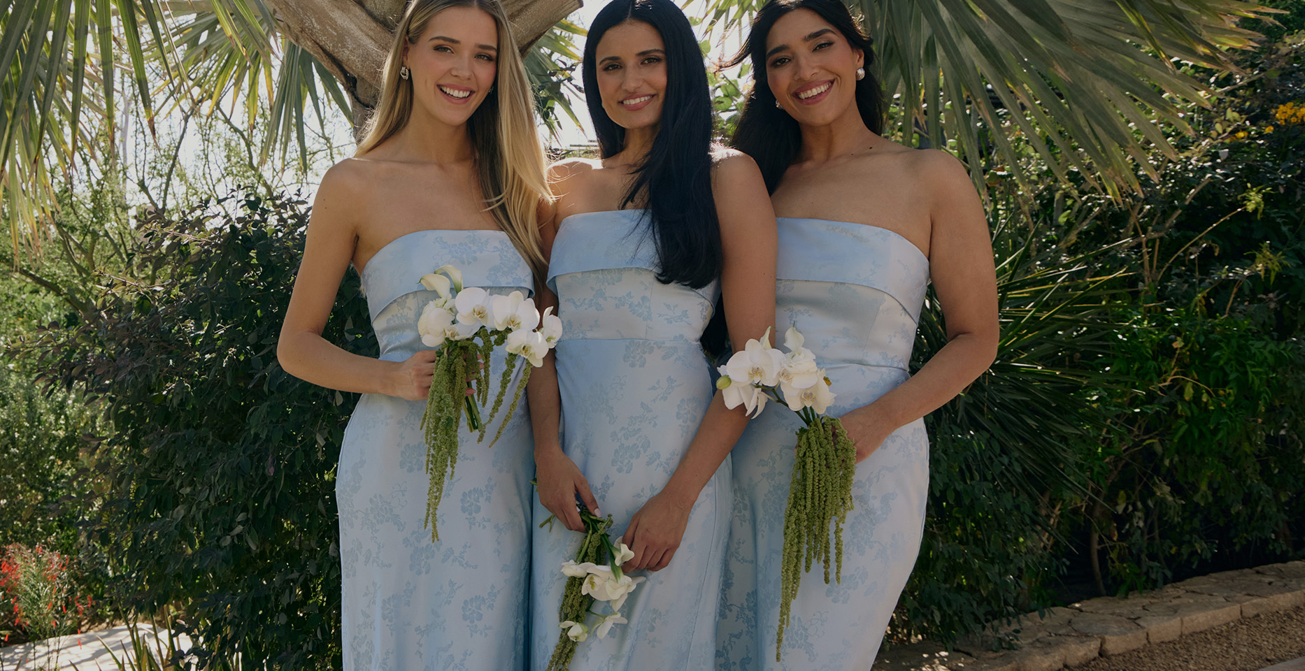 Three women in light blue dresses holding white bouquets.