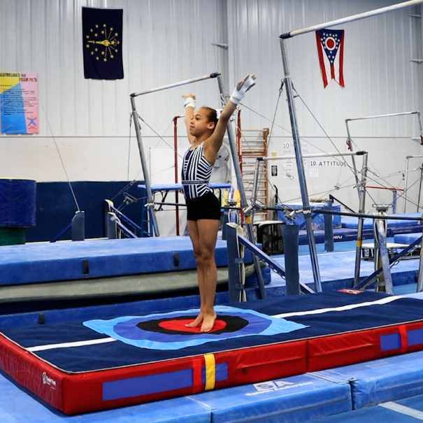 Young gymnast performing on balance beam in a gymnasium.