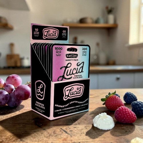 Box of Lucia products with berries and grapes on a kitchen counter.