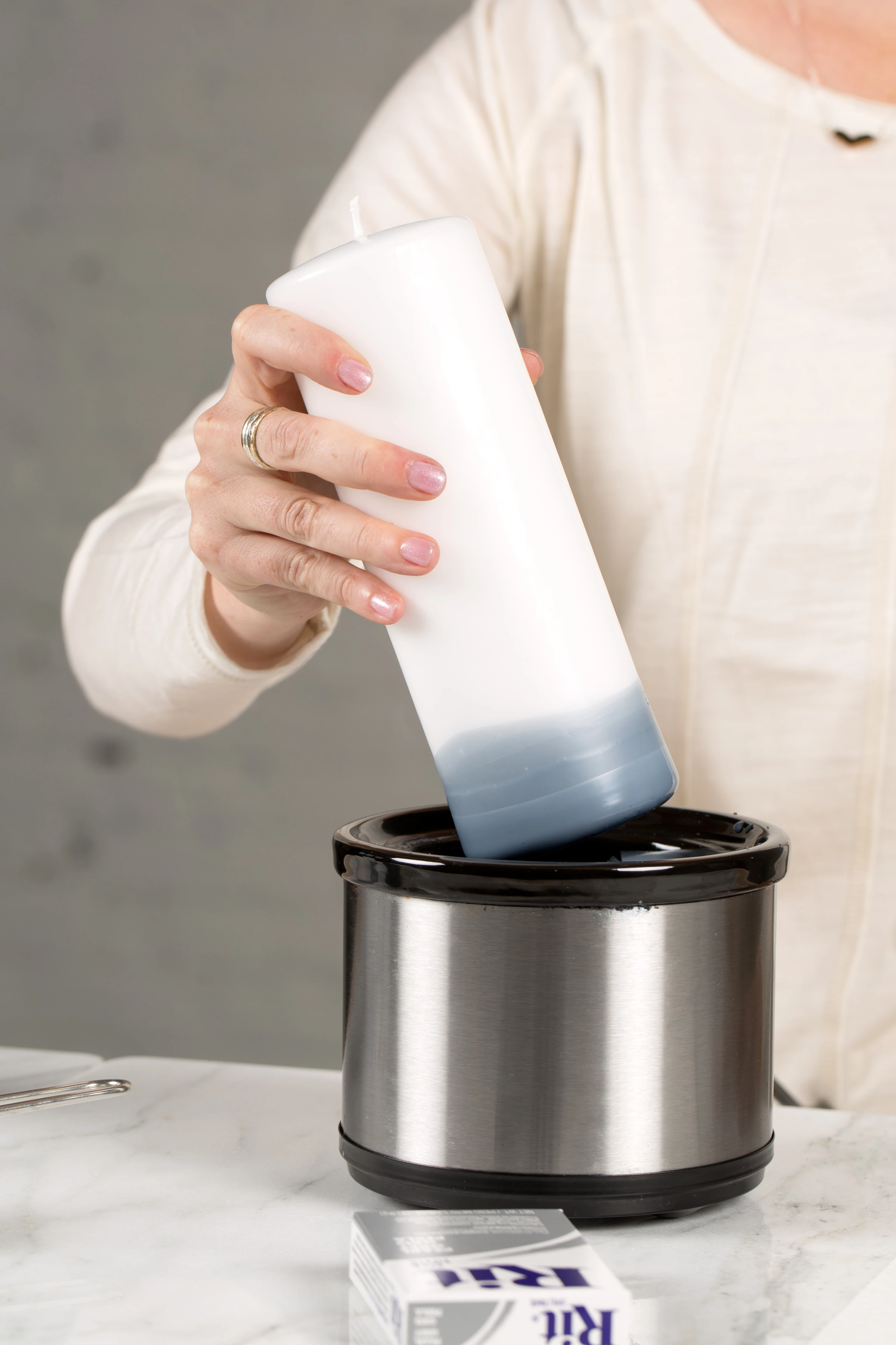 Person pouring a substance from a container into a metal bowl.