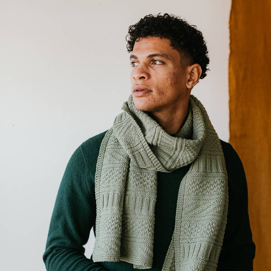 Nico, male, models Guernsey Wrap by Jared Flood, a large rectangular textured hand knit wrap in Prickly Pear colorway.