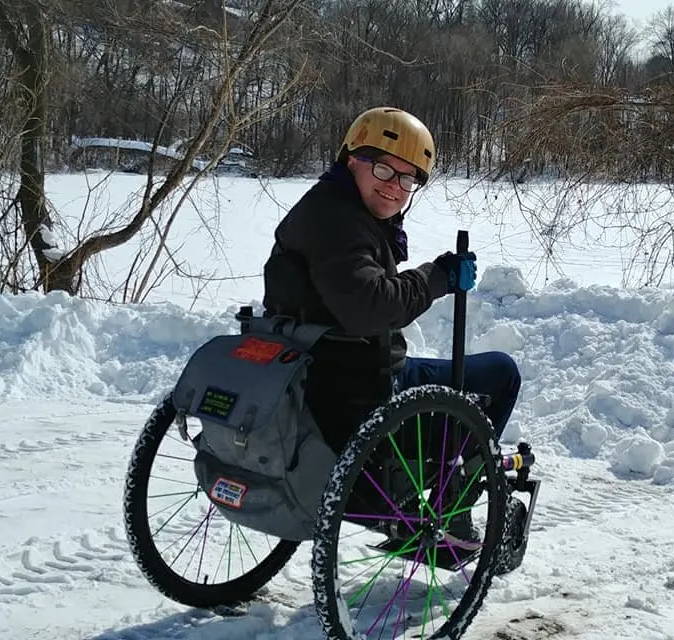 Person smiles looking back over shoulder while using GRIT Freedom Chair all terrain wheelchair on snow