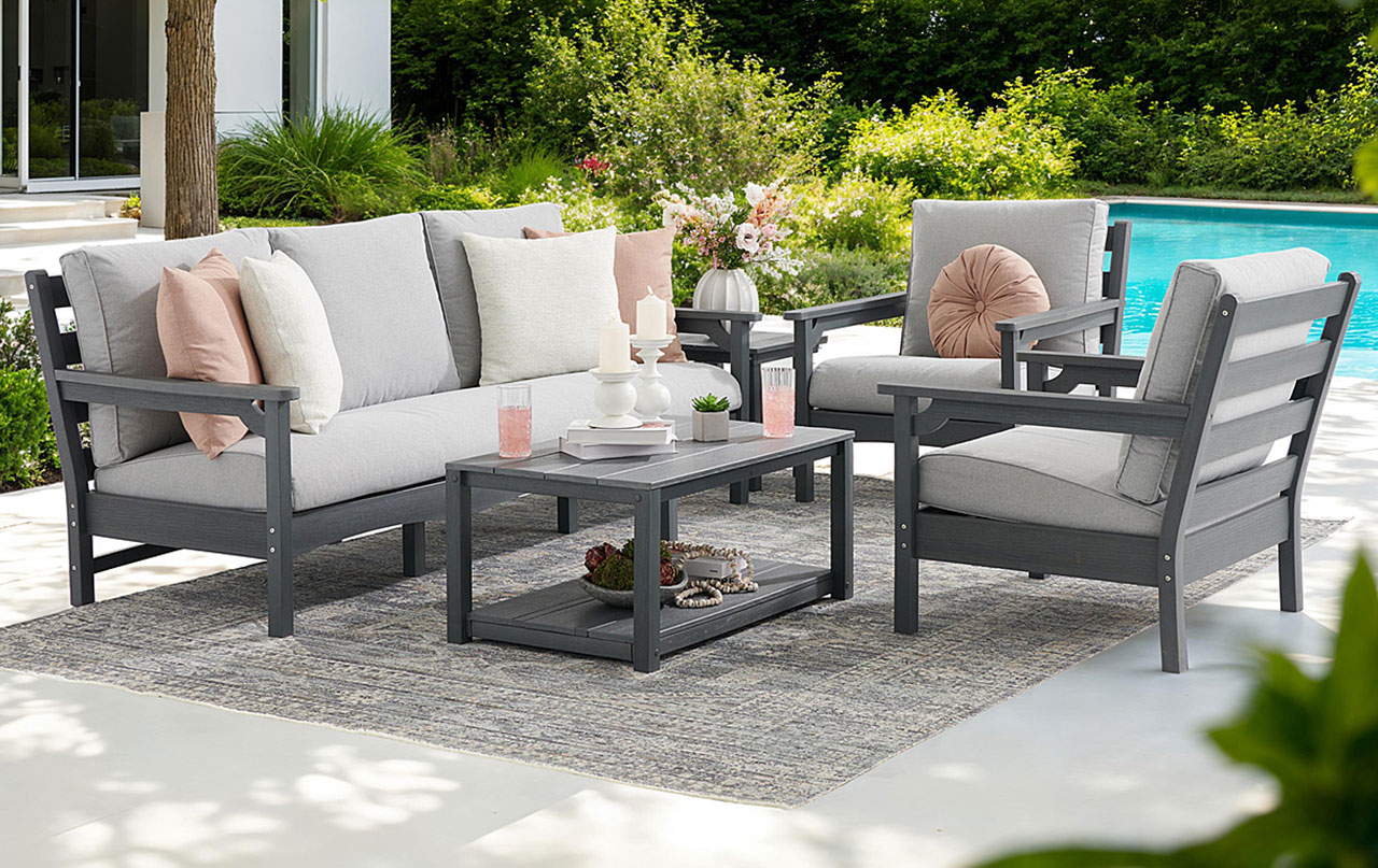 Outdoor seating area with gray furniture and cushions by a pool.
