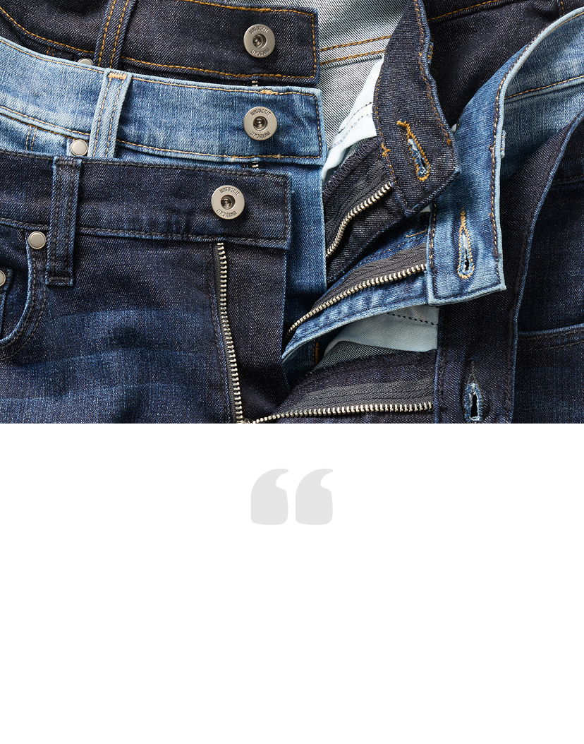 Various pairs of denim jeans stacked together, showcasing different shades of blue.