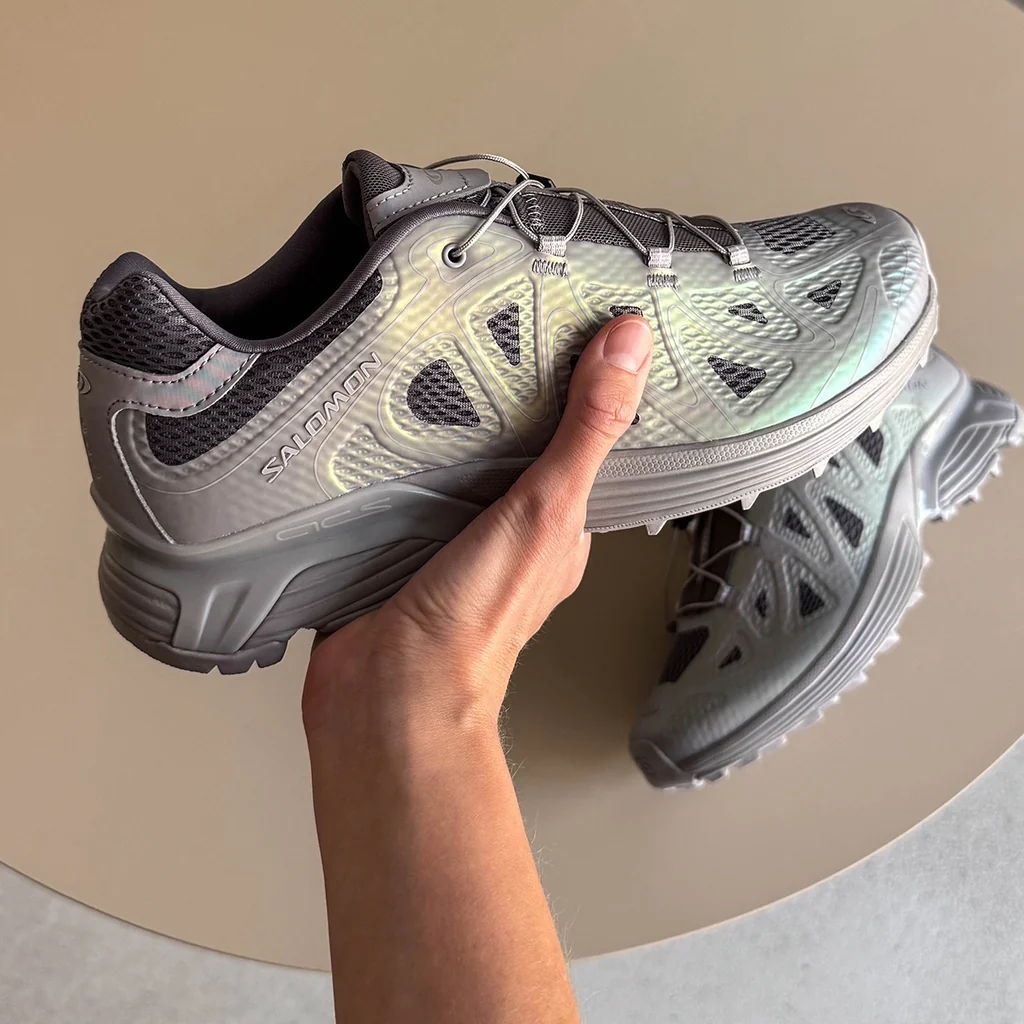 A person holding a pair of gray athletic shoes.