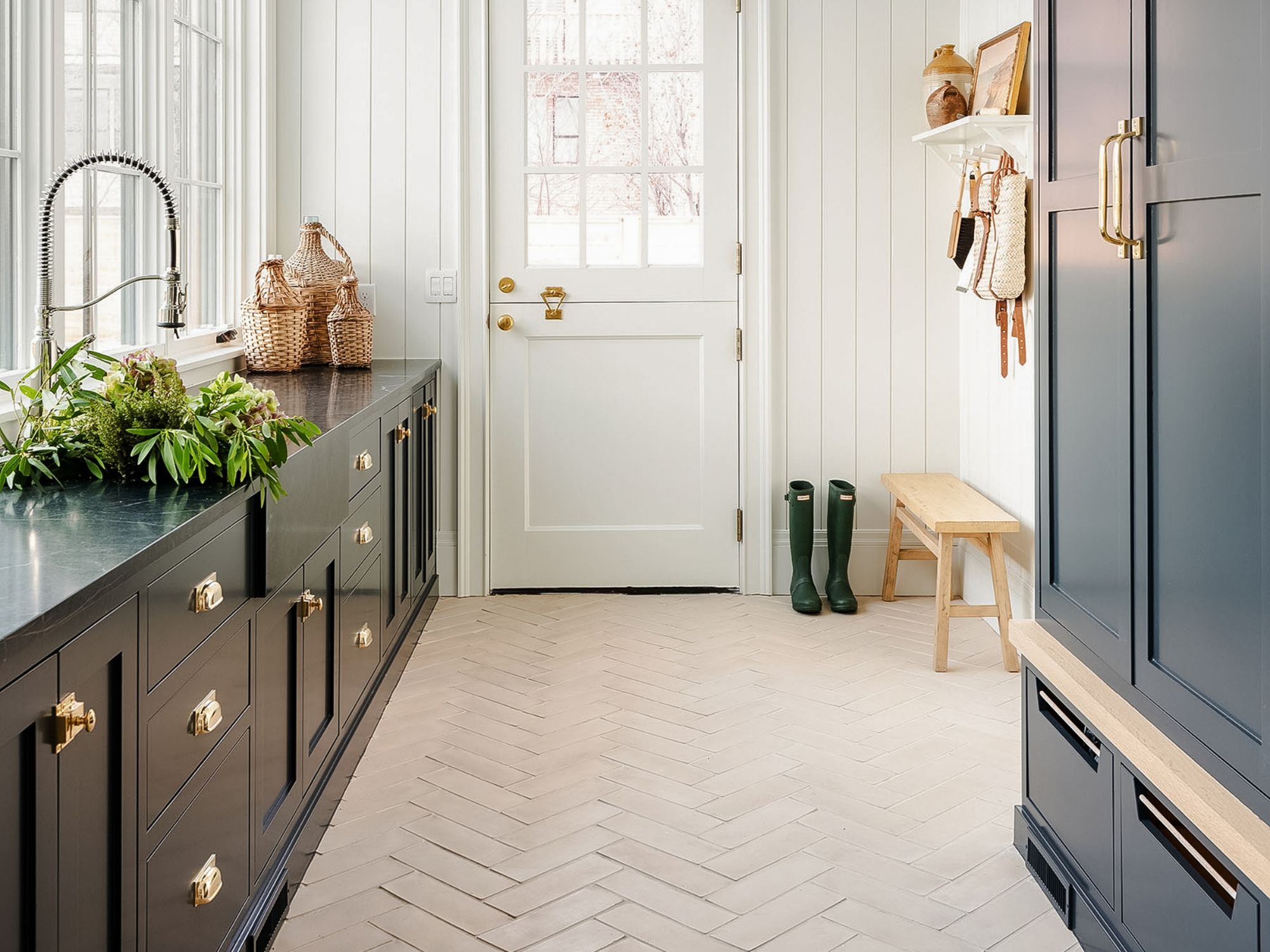 studio mcgee mudroom with dark cabinets, natural wood floor and brass hardware