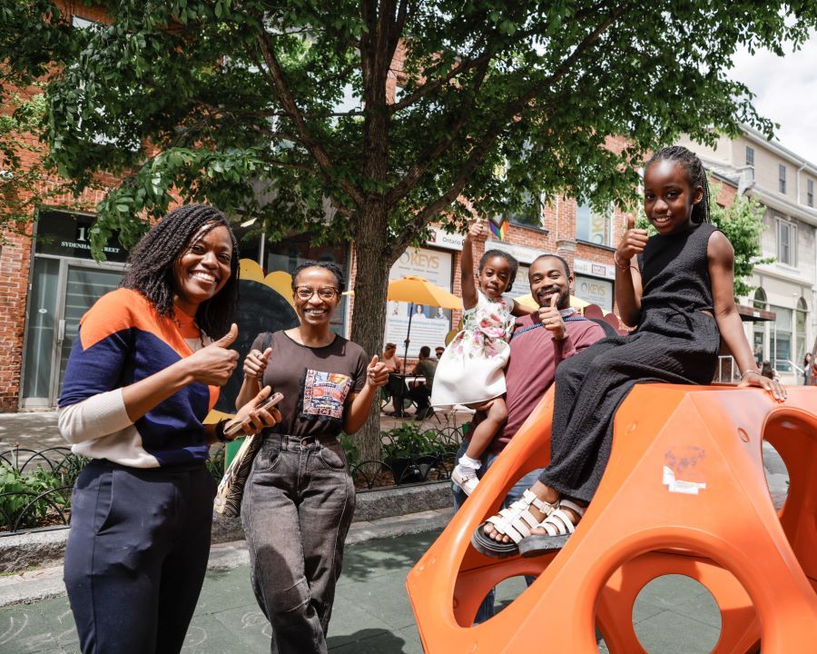 Group of people enjoying time at a playground with a colorful structure.