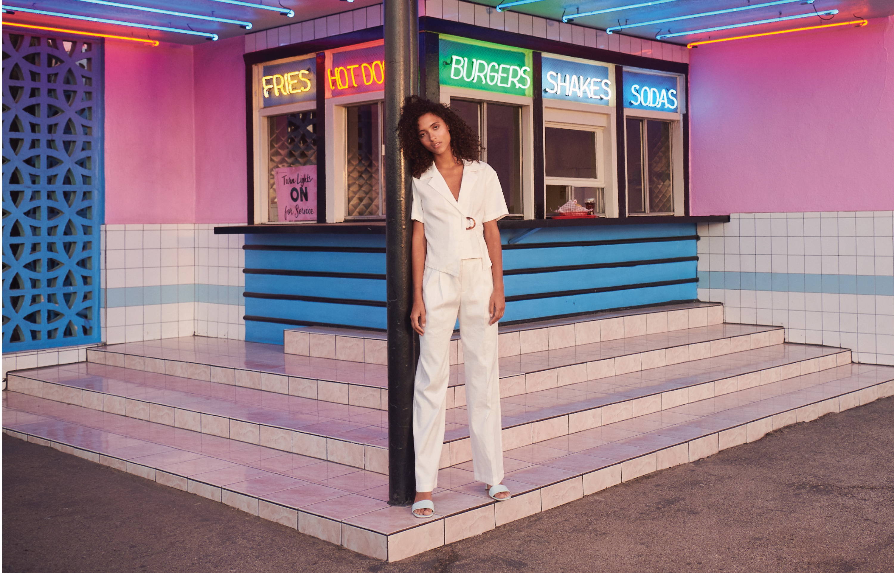 Model in front of fast food stand wearing April jacket and Marni pant in creme