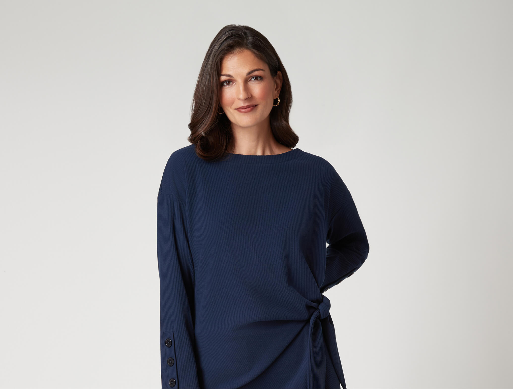 Woman in a navy long-sleeve top, standing against a neutral background.