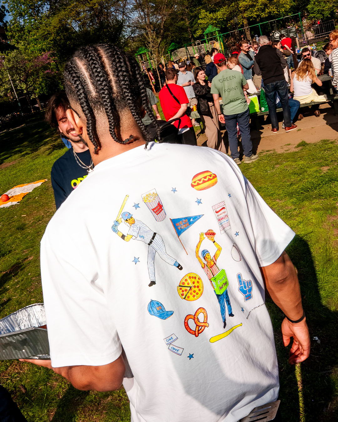 Person wearing a white shirt with colorful food-themed illustrations on the back.