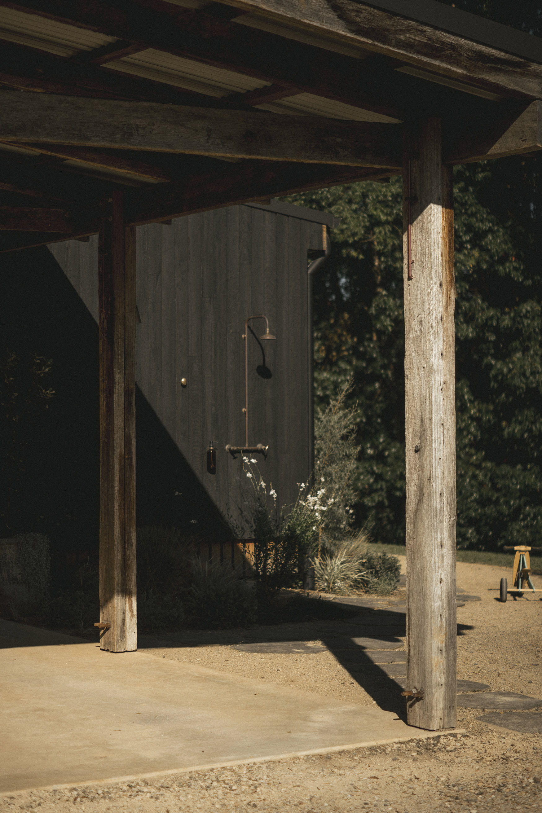 A rustic building corner with wooden posts and natural surroundings.