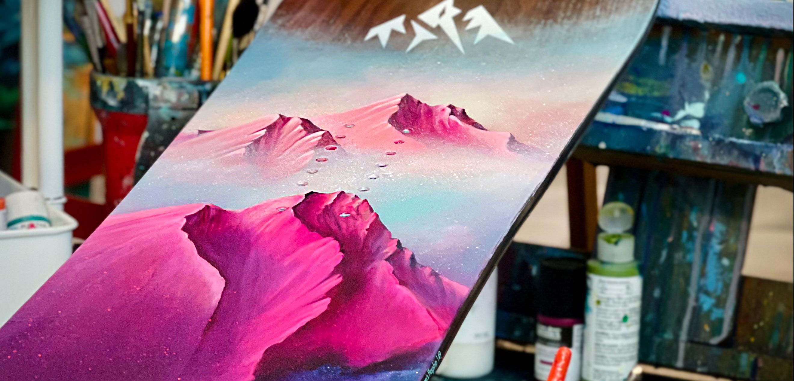 A colorful painting of mountains with pink and blue hues.